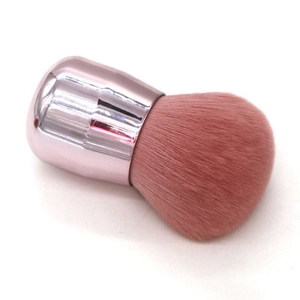 Macro detail of large rose gold mushroom makeup brush with soft pink bristles