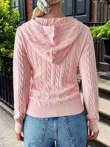 Back view of pink cable-knit hoodie for women with ribbed cuffs on stone stairs