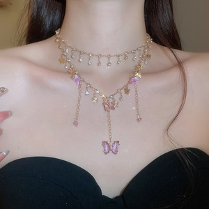 Detail of layered gold necklace with pink resin butterflies and sparkling crystals