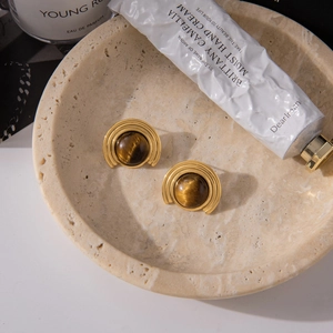 Vintage golden tiger eye earrings in a stone bowl for a luxurious lifestyle aesthetic