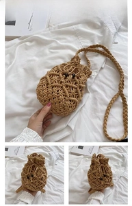 Detail of khaki woven crossbody bag with drawstring closure and wooden bead accents