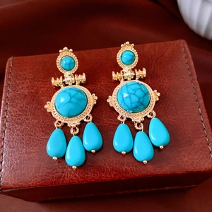 Detail view of vintage gold earrings with blue stones on a brown leather jewelry box