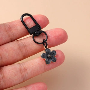 Macro shot of black enamel five-petal flower keychain charm with gold metal details