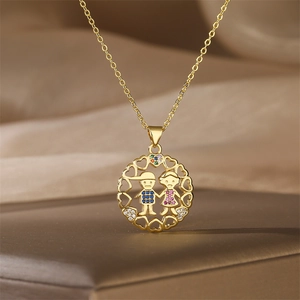 Detail of gold pendant with boy and girl figures and heart cutout pattern with colorful gems