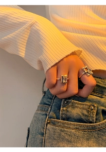 Detailed view of silver rings set with rectangular crystal and abstract design on model's hand