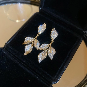 Detail of golden leaf earrings with micro-paved zircons in a luxury black velvet box