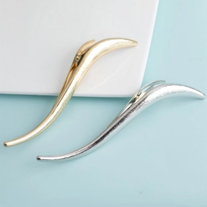 Detailed view of S-shaped minimalist hair clips in gold and silver matte metal finish