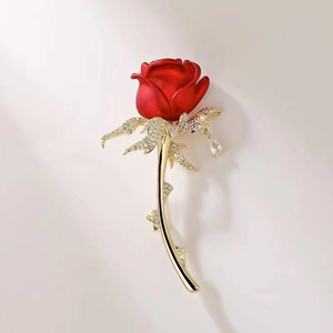 Makro-Detail der Vintage Rosenbrosche in Rot mit Goldblättern und funkelndem Kristallanhänger