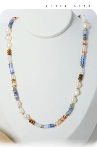 Detail of bohemian necklace featuring baroque pearls, blue stones and tiger eye beads