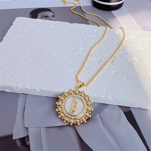 Macro detail of gold-plated Virgin Mary pendant with pearls and zircons on a twisted chain