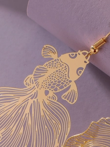 Detailed view of golden koi fish earrings with intricate hollow-out carving craftsmanship