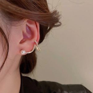 Close-up of elegant gold snake earring with white pearl and pave diamond accents
