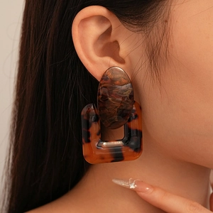 Close-up of tortoiseshell resin geometric earrings worn on a model's ear