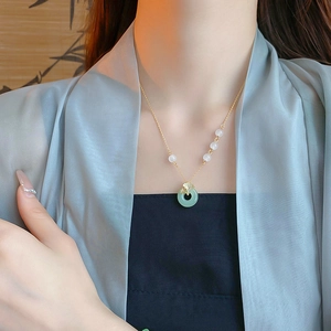 Détail d'un collier en jade avec feuille de ginkgo dorée sur un mannequin