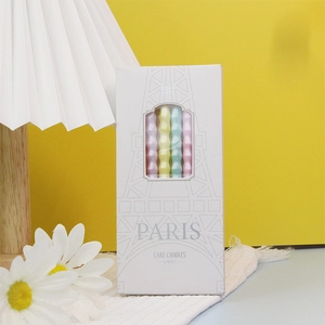 Macro detail of 6-piece colorful wavy macaron birthday candles in Eiffel Tower packaging