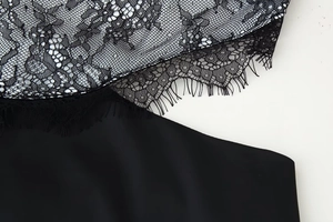 Detailed close-up of intricate black lace patterns and delicate eyelash trim on dress