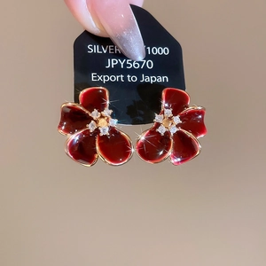 Close-up of vintage flower earrings with burgundy enamel and 18K gold plating