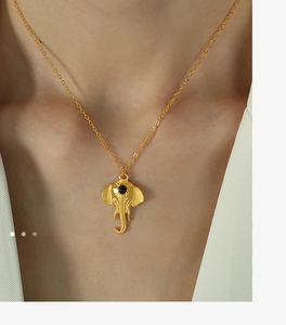 Detail of a golden elephant pendant necklace with a black gemstone on a model
