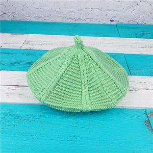 Detailed knit texture and top detail of a mint green braided beret on wooden background