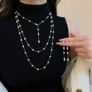 Gros plan d'un collier de perles multicouches vintage et de boucles d'oreilles pendantes