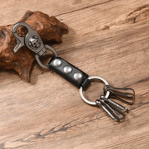 Detail of vintage leather keychain with metal skull hook and rivets on wood surface