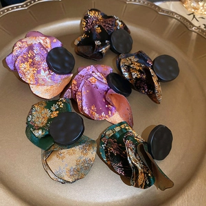 Detail of floral fabric petal earrings in assorted colors on a gold metal jewelry tray