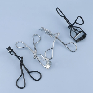 Set of four stainless steel eyelash curlers in silver and black on blue background