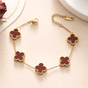 Close-up of a double-layered gold stainless steel bracelet with five red clover charms