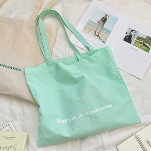 Flat lay of mint green canvas tote bag with Magasin de Croissants text and magazine