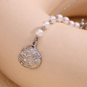 Close-up of a silver shell pendant with inlaid crystals and pearl chain detail