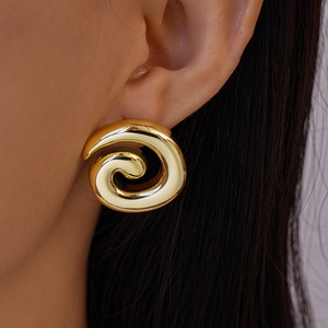 Close-up of elegant gold spiral disk earrings worn by model with metallic finish