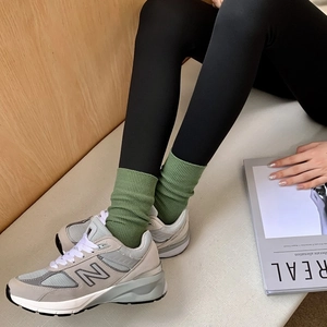 Detail shot of light grey cotton ribbed socks paired with vintage style sneakers on a sofa