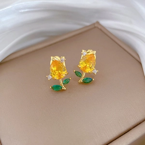 Macro detail of tulip earrings with yellow crystals and green leaf stones on silk