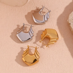 Detail of layered U-shaped earrings in gold and silver finish on textured stone