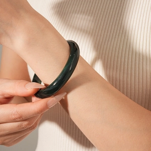 Close-up of deep green round bangle showing smooth texture and elegant luster on wrist