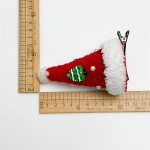 Detail of red mini Christmas hat hair clip with plush trim and green tree decoration