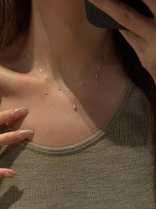 Detail view of a gold tassel necklace with pear-shaped cubic zirconia on collarbone