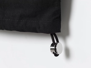 Macro view of nylon puffer jacket hem featuring metallic toggle and elastic drawstring