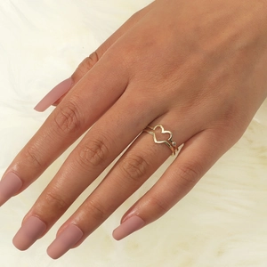 Dettaglio di un anello cuore dorato minimalista con zircone su sfondo di pelliccia bianca