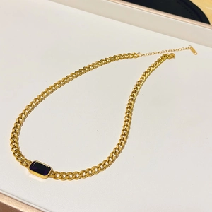 Macro shot of gold Cuban link chain necklace with rectangular purple gemstone detail