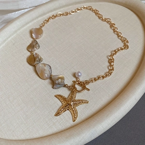 Close-up of golden starfish pendant with irregular shells and toggle clasp on a necklace
