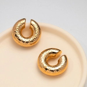 Close-up of golden hammered texture hollow ear cuffs on a ceramic tray display