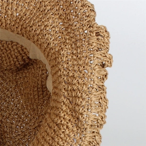 Close-up of natural straw hat with detailed crochet texture and wavy brim design