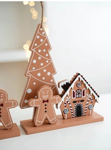 Cozy Christmas scene with wooden gingerbread man, candy house and tree table decor