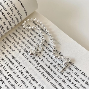 925 silver beaded heart charm bracelet with T-bar clasp displayed on an open book