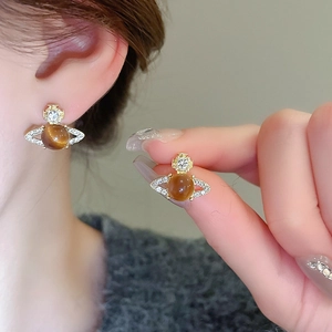 Macro shot of gold-plated planet stud earrings with cat eye stone and sparkling diamonds