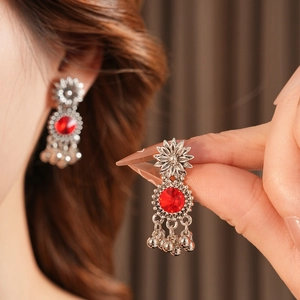Detail of vintage flower earrings with red stones and silver bells on model