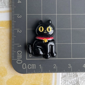 Detail view of a black cat resin charm on a cutting mat showing its 3cm height dimensions