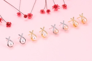 Detailed view of crisscross pearl earrings with rhinestones in gold and silver finishes