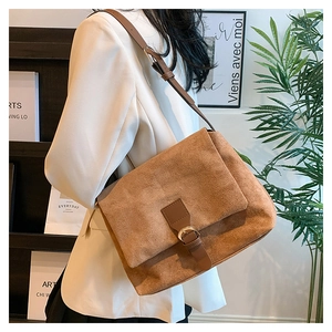 Brown faux suede tote bag with leather strap worn by a model in a white blazer